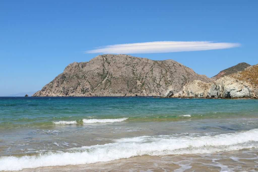 brown and green mountain beside sea during daytime