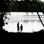 silhouette of couple standing near body of water during daytime