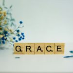 a wooden block that says grace next to a bouquet of flowers
