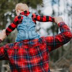 a man holding a child in his arms in the woods