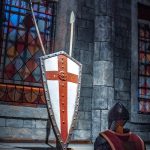 A knight standing in front of a shield and sword