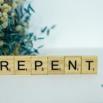 a wooden block that says repent next to a bouquet of flowers