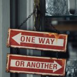 two red and white signs hanging from a metal pole